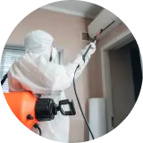 a man in ppe kit spraying chemical in a house for infection from covid and other viruses