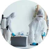 two men in ppe kit spraying disinfection chemical inside a room